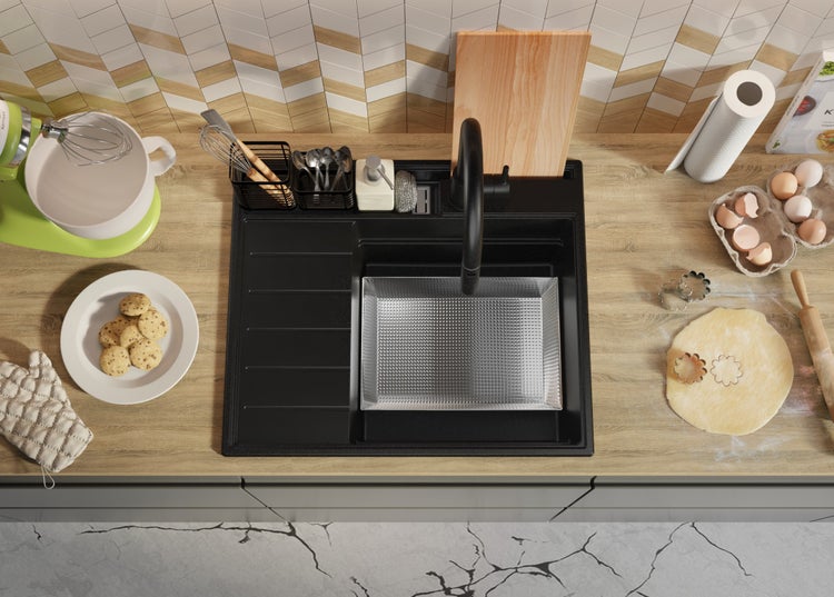 Küchenszene mit Spüle, Armatur und verschiedenen Küchenutensilien auf einer Arbeitsfläche.