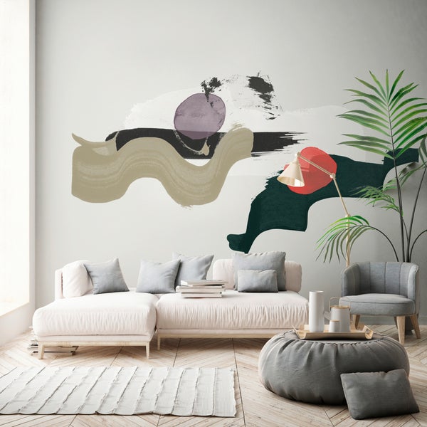Helles Wohnzimmer mit moderner Fototapete mit abstrakten Pinselstrichen, modularem Sofa, grauem Sessel und großer Zimmerpflanze.