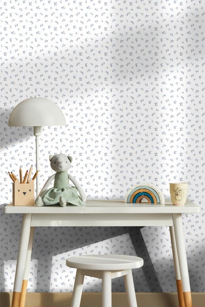 Kinderschreibtisch mit Stuhl, Lampe und Spielzeug vor einer weißen Tapete mit Blumenmuster.