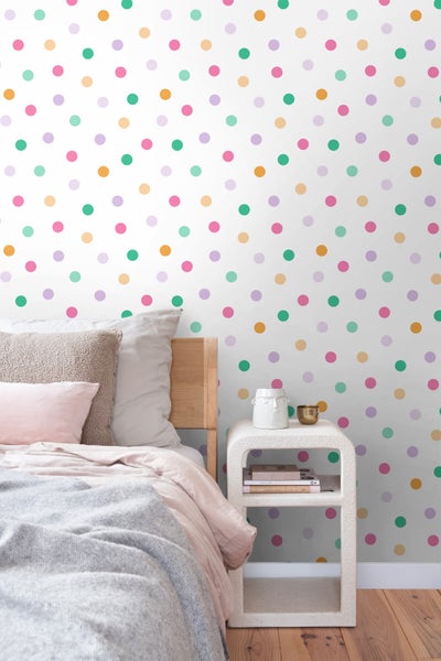 Schlafzimmer mit Bett, Nachttisch und gepunkteter Tapete