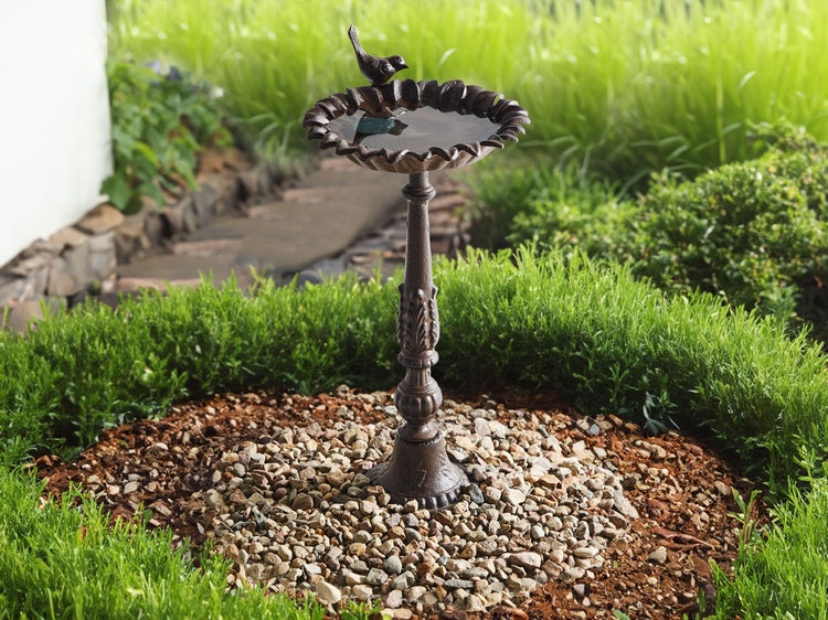 Dekorative Vogeltränke mit Vogel-Figur im Garten