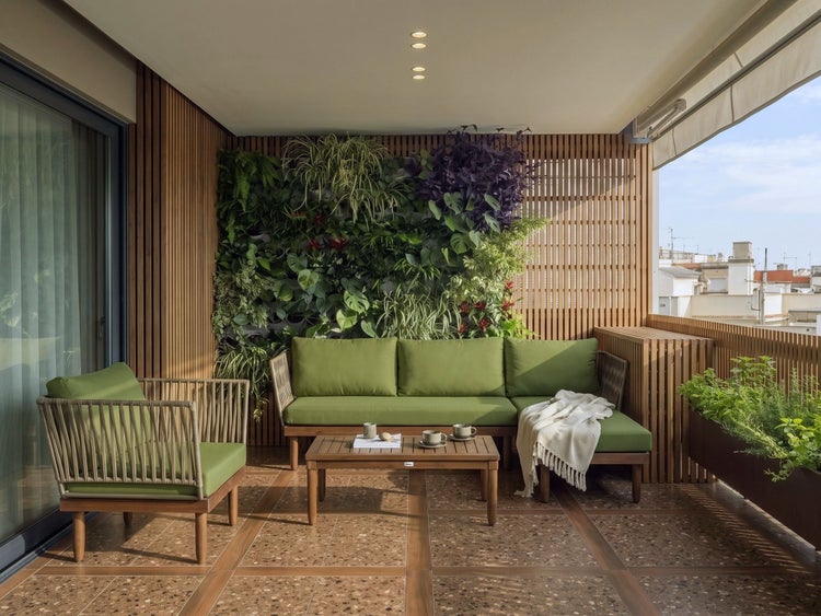 Balkon mit modernen Gartenmöbeln aus Holz, grünen Polstern, vertikalem Garten, Holzlattenverkleidung und gefliestem Boden.