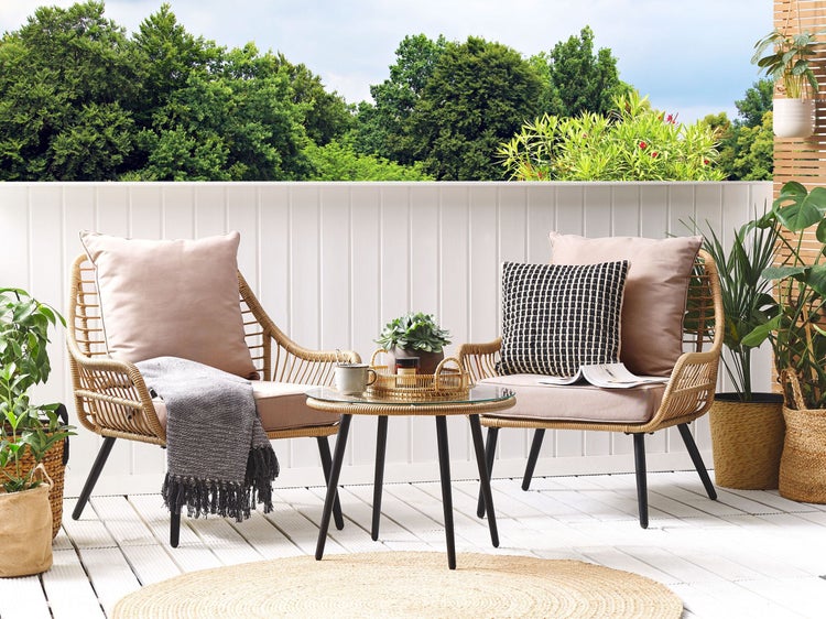 Gartenmöbel-Set mit zwei Rattansesseln, Tisch mit Glasplatte und Dekoration auf einer Terrasse