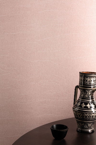 Grauer Teppich mit rotem und silberfarbenem Muster und rutschfester Rückseite wird von einer Hand angehoben.