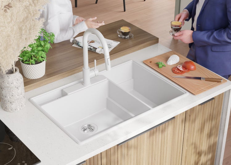 Küchenspüle mit Abtropffläche, Armatur, Schneidebrett mit Zutaten und Kaffeetassen auf der Arbeitsfläche