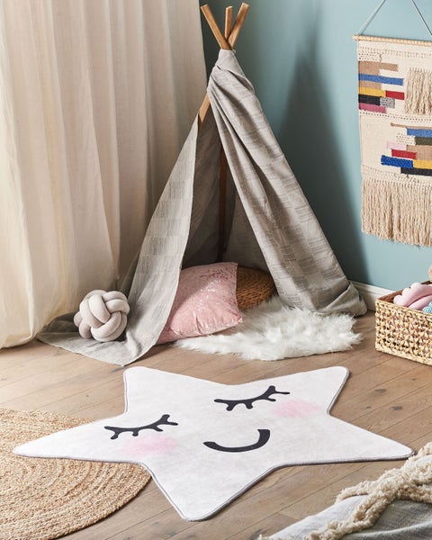 Verspieltes Kinderzimmer mit Sternteppich, Tipi und dekorativen Textilien.