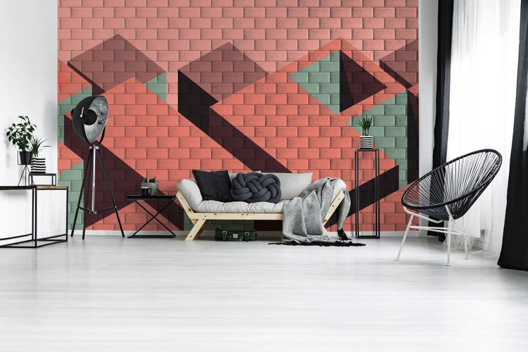 Fototapete mit dreidimensionalem geometrischem Muster in Backsteinoptik in einem hellen, modernen Wohnzimmer mit Sofa und Stativlampe.