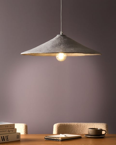 Hängelampe mit konischem Schirm und eingeschalteter Glühbirne über einem Holztisch