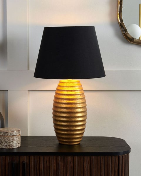 Dekorative Tischleuchte mit schwarzem Lampenschirm und goldenem Sockel auf einem Tisch