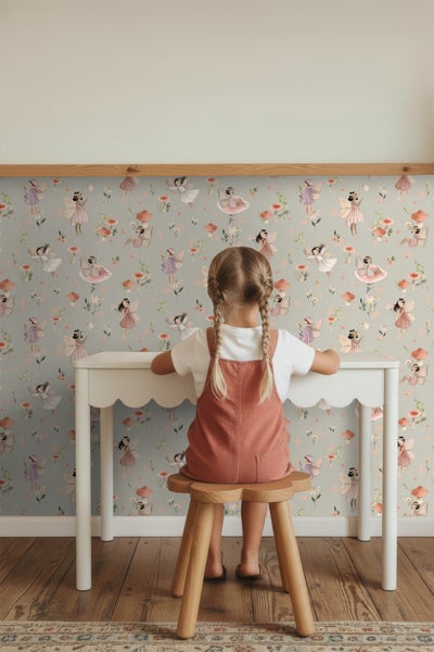 Kind sitzt an einem Tisch vor einer Tapete mit Feen-Motiv