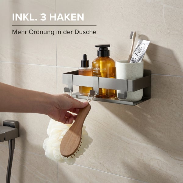 Duschablage aus Metall in Anthrazit mit drei Haken, an der Wand montiert, mit Badutensilien und einer Hand, die eine Bürste aufhängt.