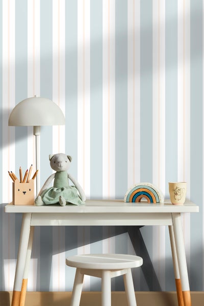 Kinderschreibtisch mit Lampe, Bärenpuppe und Spielzeug vor gestreifter Tapete