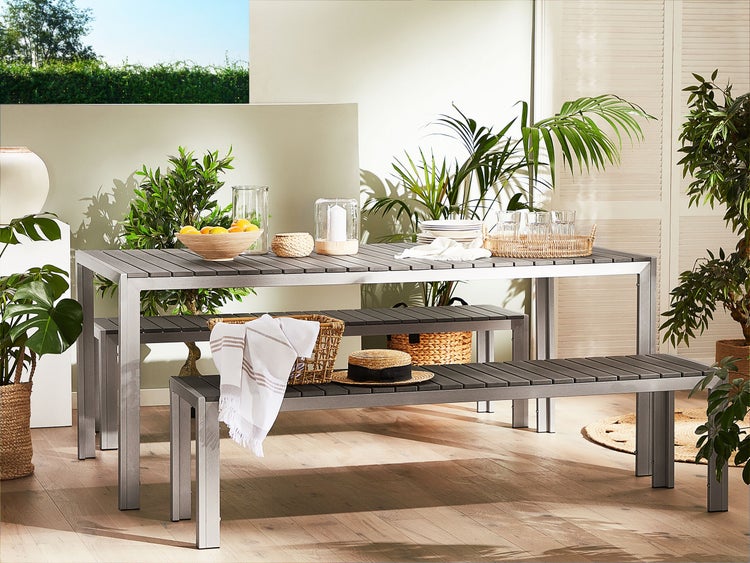 Gartensitzgruppe mit Tisch und Bank, dekoriert mit Pflanzen und Accessoires für eine einladende Atmosphäre im Freien.