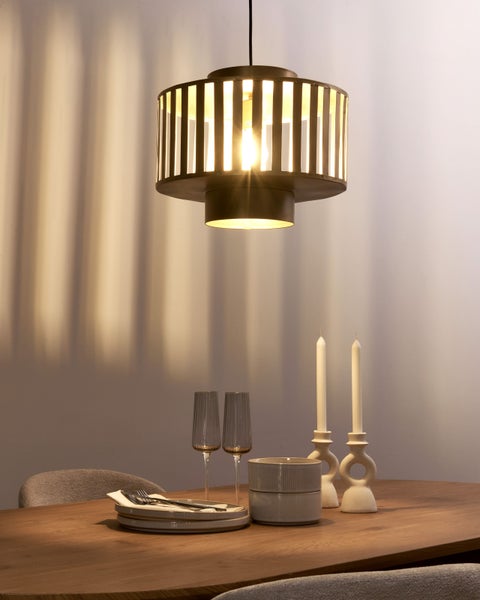 Esstisch-Szene mit Pendelleuchte, Geschirr, Gläsern und Kerzenständern für eine warme Atmosphäre.