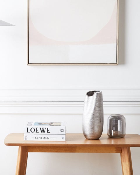 Dekorative Szene mit Tisch, silberner Vase und Wohnaccessoires