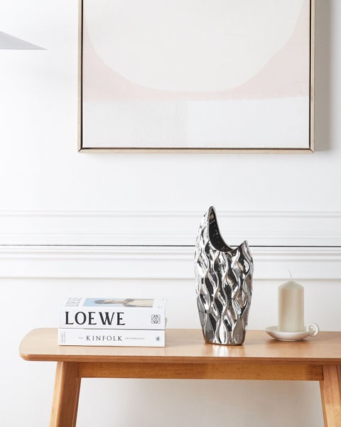 Dekorative Vase mit gewellter Oberfläche in den Händen gehalten.