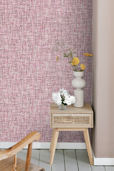 Raumansicht mit rosafarbener Tapete, Nachttisch und Dekorationsartikeln
