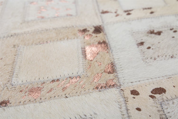 Nahaufnahme eines Patchwork-Teppichs aus Kuhfell mit metallischen kupferfarbenen Flecken und Ziernähten.