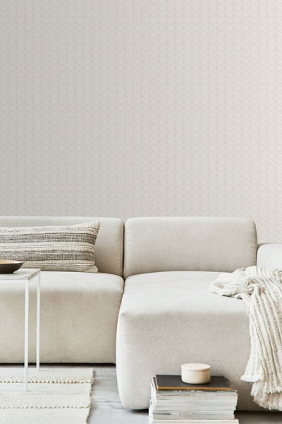 Dekoratives Kinderzimmer mit einer Tapete mit Dinosaurier-Motiven und Stofftieren auf einem Stuhl.