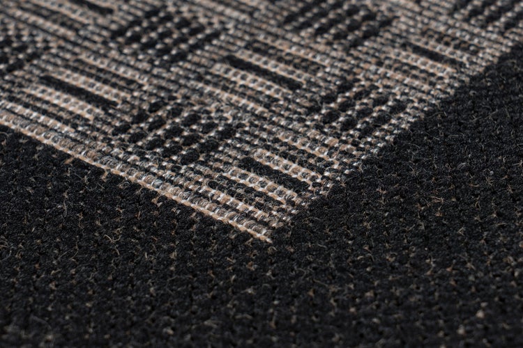 Nahaufnahme eines Teppichs mit gewebter Struktur und geometrischem Muster aus Streifen und Quadraten.