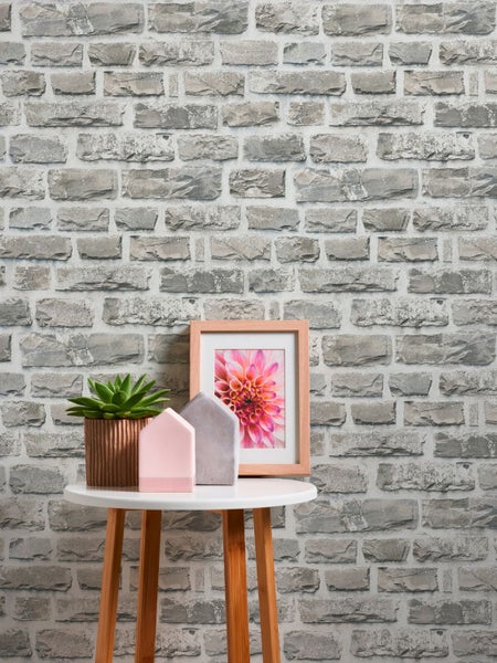 Dekorative Steinmauer Tapete hinter Tisch mit Pflanzen, Häusern und gerahmten Bildern