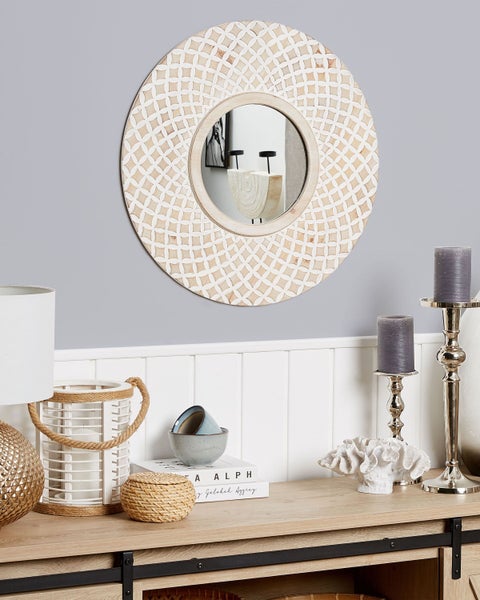 Dekoratives Interieur mit einem runden Wandspiegel über einem Sideboard mit Dekorationsgegenständen