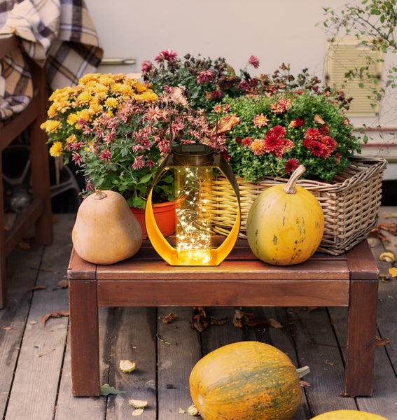 Dekorative Szene mit Solarleuchte und Blumenstrauß auf einem Tisch im Freien.