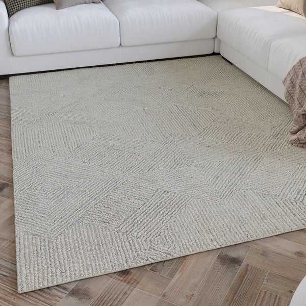 Moderner Teppich mit geometrischem Webmuster vor einem weißen Sofa auf Holzboden im Wohnzimmer.