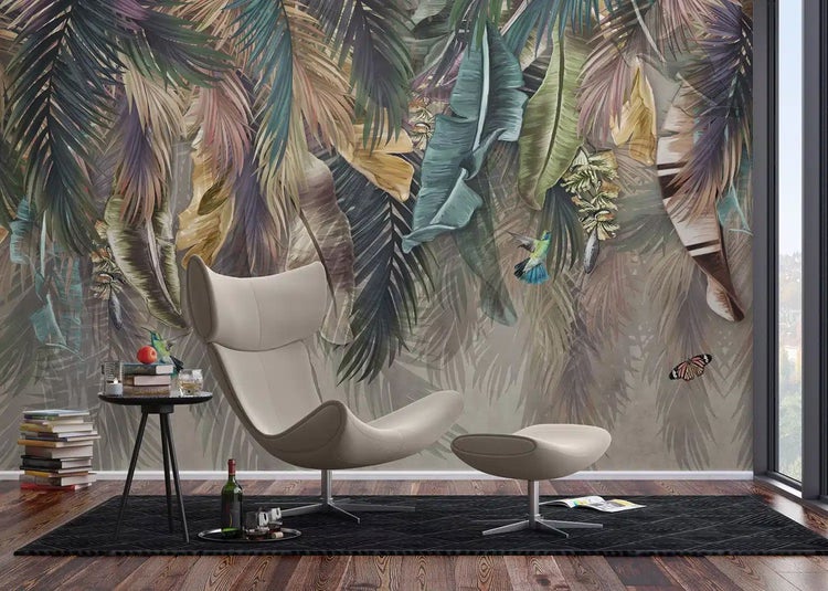 Fototapete mit tropischem Blättermotiv, Kolibris und Schmetterling in einem modernen Wohnzimmer mit Loungesessel und Hocker.