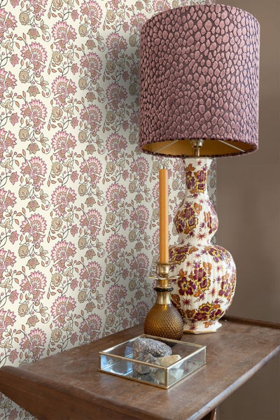 Dekoratives Interieur mit floraler Tapete, Tischlampe und Kerzenständer auf einem Holztisch.