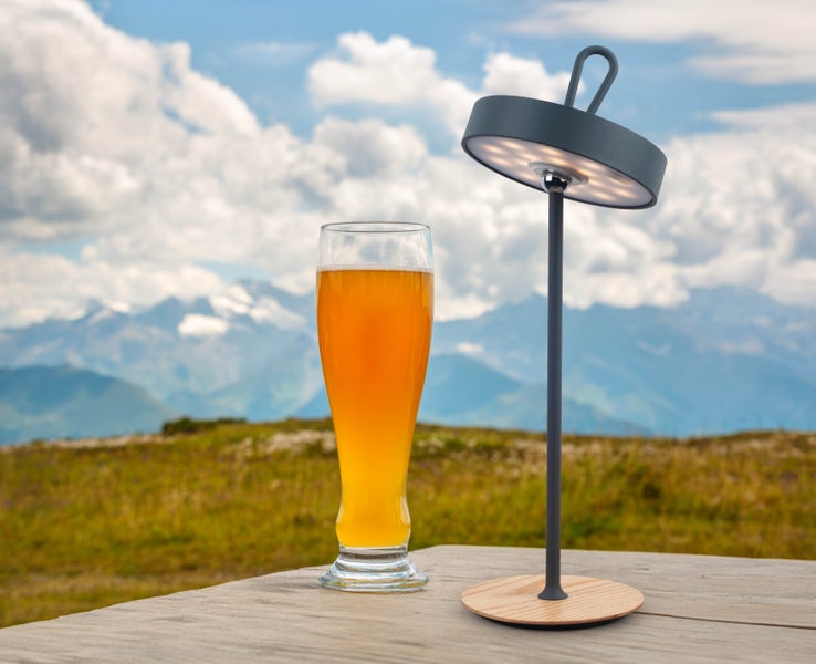 Szene mit einem Glas Bier und einer tragbaren LED-Tischleuchte im Außenbereich
