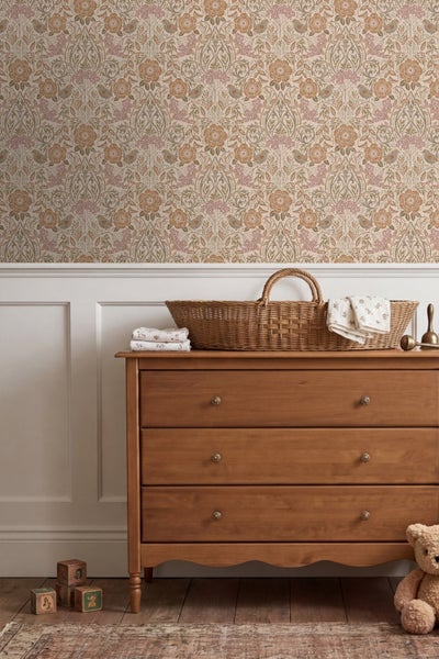 Vliestapete mit floralem Muster und Vögeln über einer weißen Wandvertäfelung in einem Kinderzimmer mit Holzkommode und Weidenkorb.