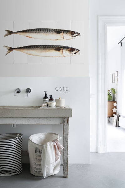 Heller Raum mit Waschbecken, Wäschekörben und einer Fisch-Wanddekoration für ein helles und organisiertes Ambiente.