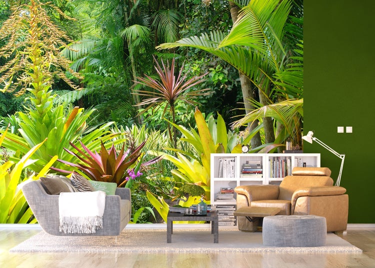 Wohnzimmer mit tropischer Pflanzen-Fototapete, Sesseln, Beistelltisch und Bücherregal.
