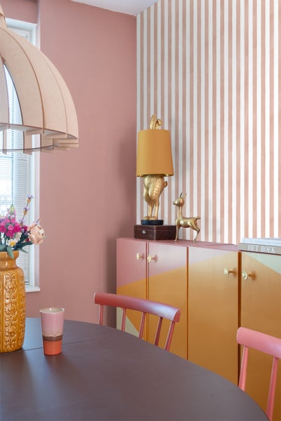 Esszimmer mit Esstisch, Stühlen, Schrank, Tischlampe und dekorativen Accessoires in einem Haus