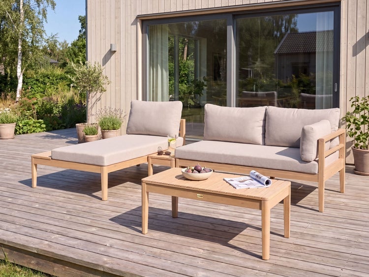 Holz-Lounge-Set auf einer Holzterrasse mit Liege, Sofa und Couchtisch vor einem modernen Wohnhaus mit großen Fenstern.