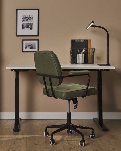 Ein höhenverstellbarer Schreibtisch mit einem Bürostuhl, einer Lampe und Bürobedarf.