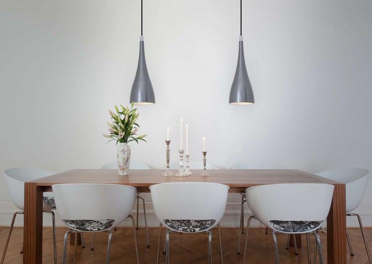 Esstisch mit Stühlen, Blumenvase, Kerzenleuchtern und Pendelleuchten für eine helle und organisierte Atmosphäre