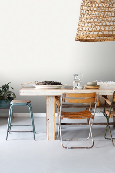 Esstisch mit Stühlen, Geschirr und dekorativem Obst unter einer Korbleuchte