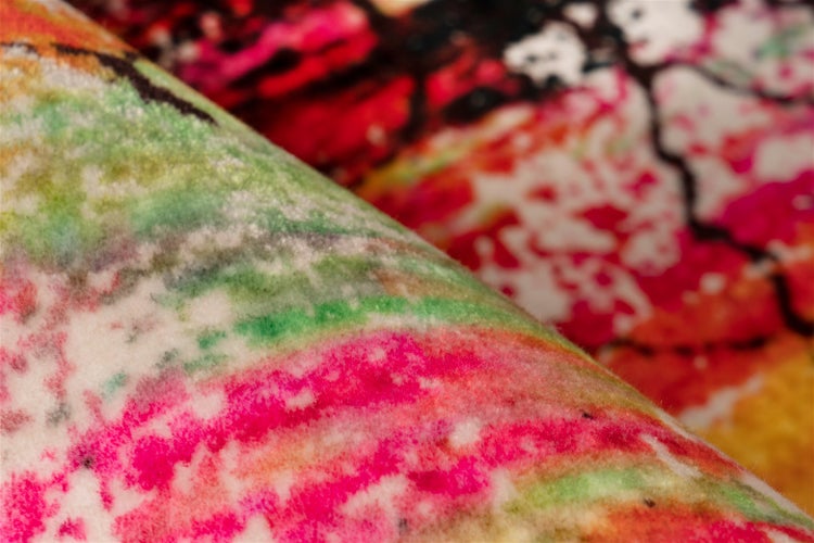 Rechteckiger, mehrfarbiger Teppich mit abstraktem, rissigem Muster.