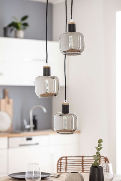 Hängelampe mit drei Leuchten und klaren Glasschirmen in einem hellen Küchenambiente.
