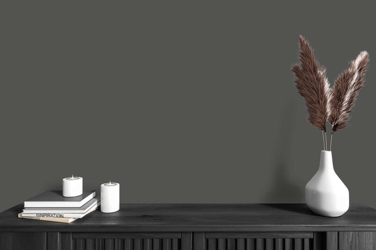 Matte dunkelgraue Wandfarbe in einem modern gestalteten Raum mit dunklem Sideboard, Büchern und weißer Vase.