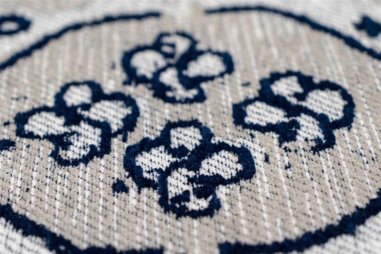 Nahaufnahme eines gewebten Teppichs mit floralem Muster und vertikaler Struktur.