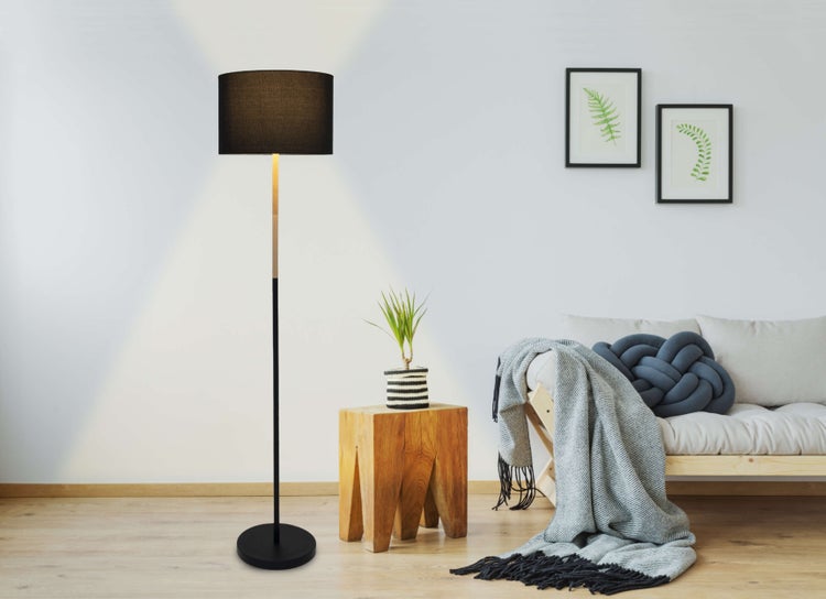 Wohnzimmer mit Stehlampe, Sessel und Holzkommode mit Dekorationen.