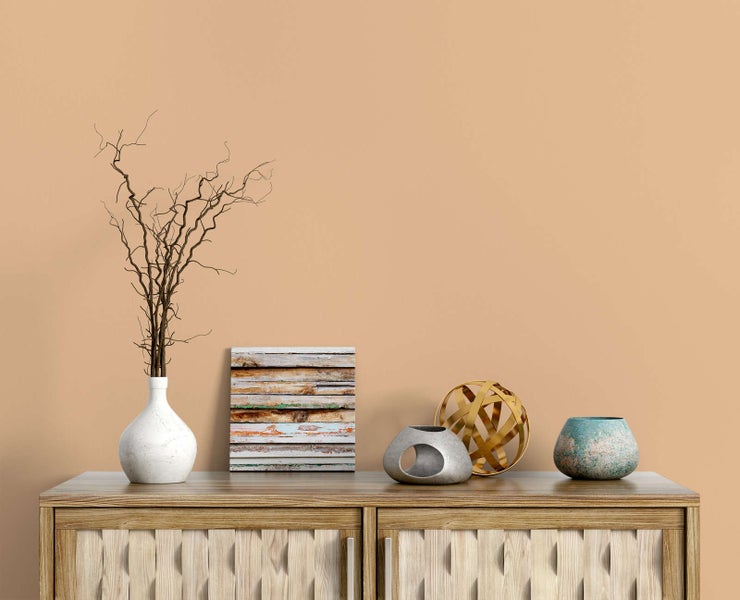 Hölzernes Sideboard mit Dekorationsartikeln wie einer Vase mit Zweigen, einem quadratischen Wandbild und abstrakten Skulpturen.