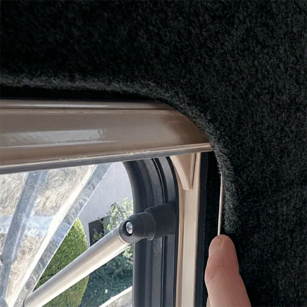 Detailansicht einer Fensterverkleidung mit Textilbezug in einem Fahrzeug.