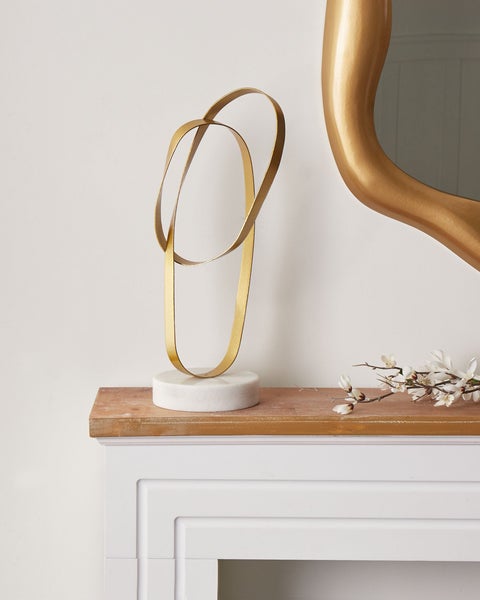 Dekorative goldfarbene Ringskulptur auf Marmorsockel