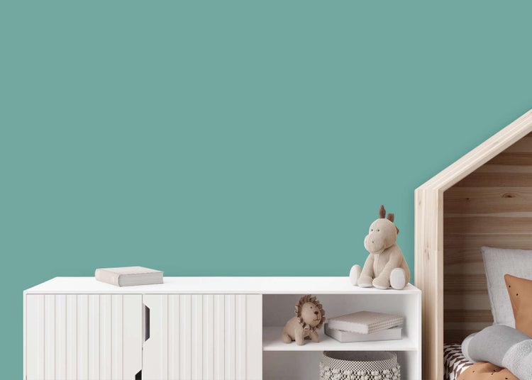 Helle Kinderzimmer-Einrichtung mit türkis gestrichener Wand, weißem Sideboard und einem Hausbett aus Holz.