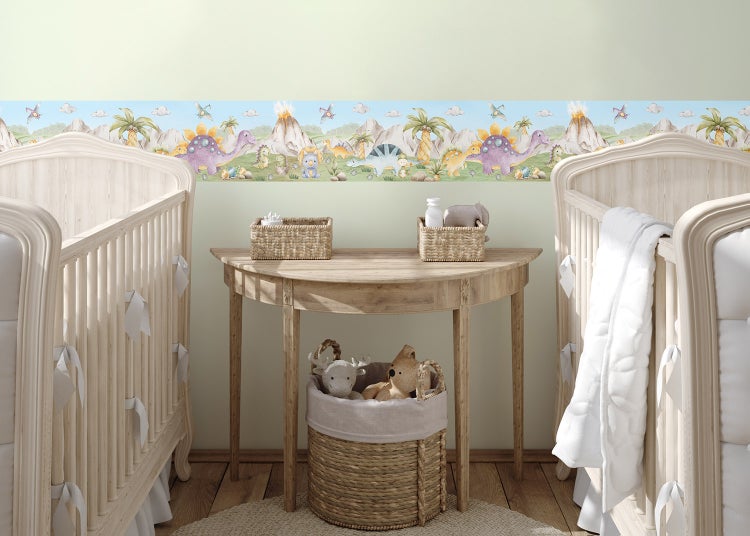 Tapetenborte mit Dinosaurier-Motiv in einem hellen Kinderzimmer mit zwei Gitterbetten aus Holz und einem geflochtenen Korb.