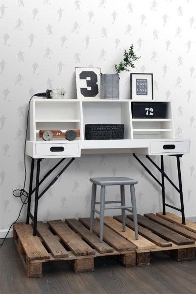 Schreibtisch mit Regalen und Ablagefächern, mit einem Hocker und auf Holzpaletten stehend, dekoriert mit verschiedenen Gegenständen.